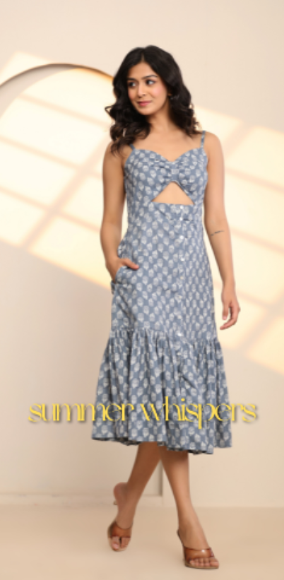 Woman wearing a blue patterned dress with cut-out design, standing against a light background with 'summerwhispers' branding.